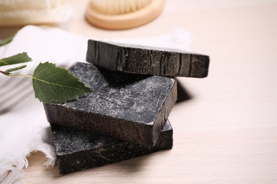 Photo of Natural tar soap and towel on wooden table, closeup