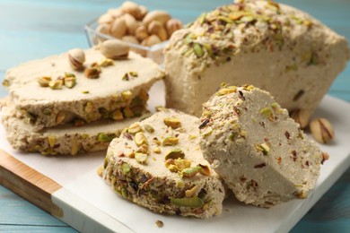 Photo of Pieces of tasty halva with pistachios on table, closeup