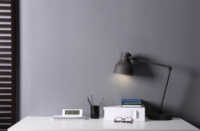 Photo of Lamp and different stationery on table in office. Space for text