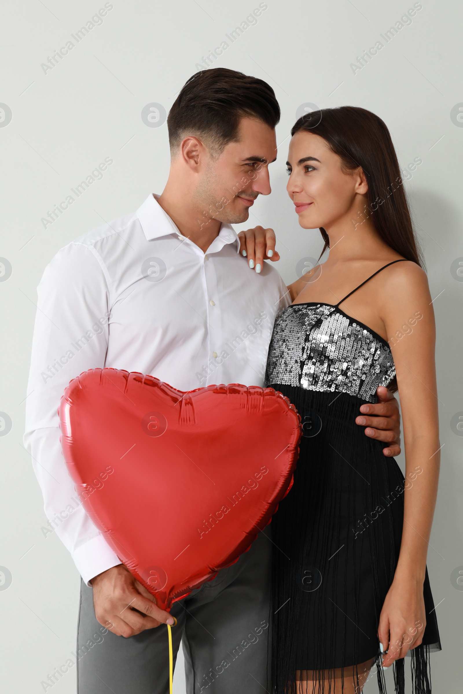 Photo of Beautiful couple with heart shaped balloon on light background