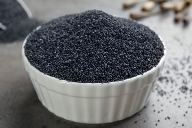 Poppy seeds in bowl on grey table, closeup