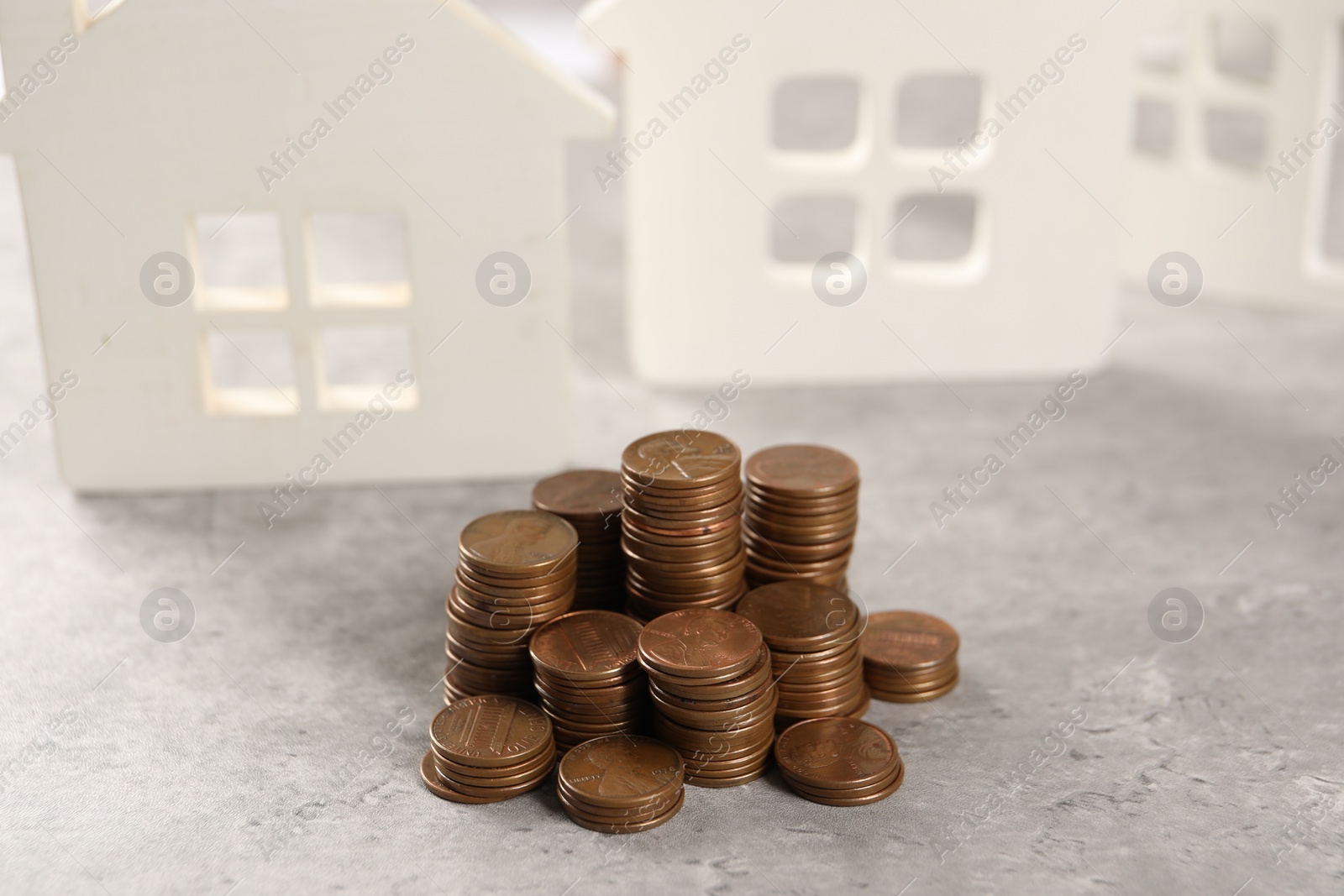 Photo of House models and stacked coins on grey table, selective focus