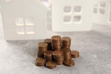 House models and stacked coins on grey table, selective focus