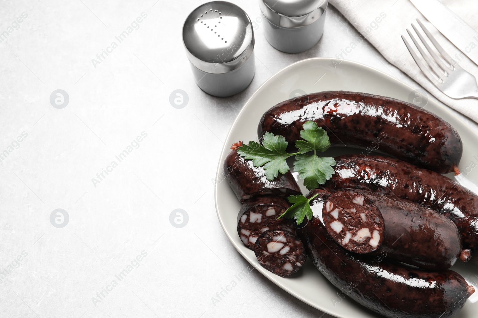 Photo of Tasty blood sausages with parsley served on light grey table, flat lay. Space for text
