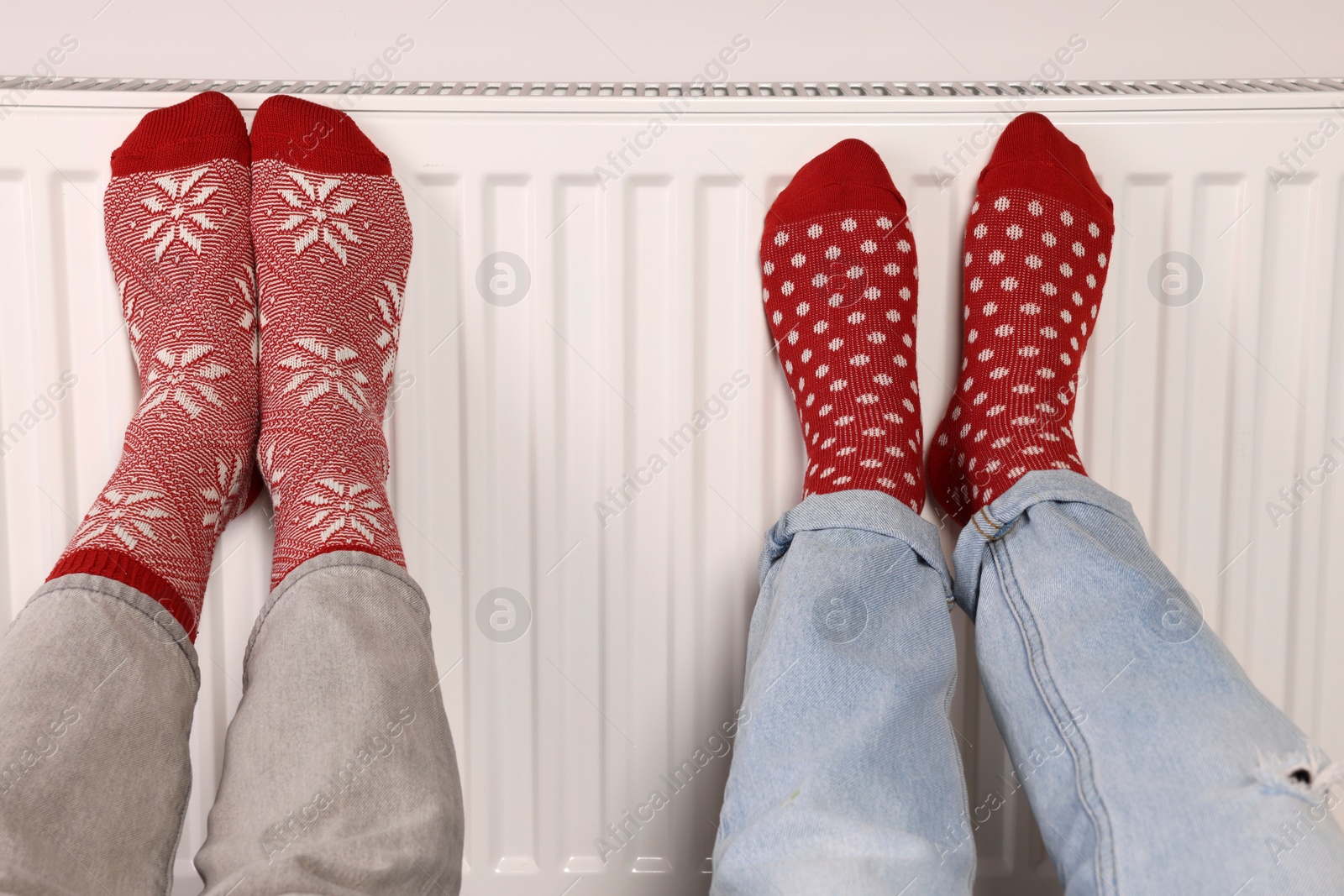 Photo of People warming feet near heating radiator, closeup