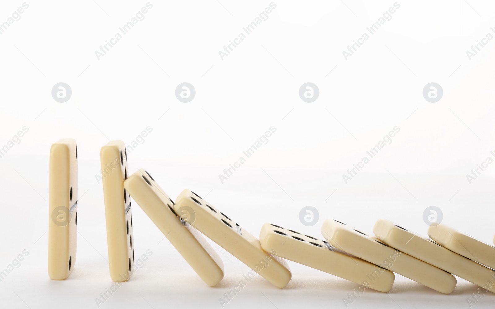 Photo of Light domino tiles falling on white background