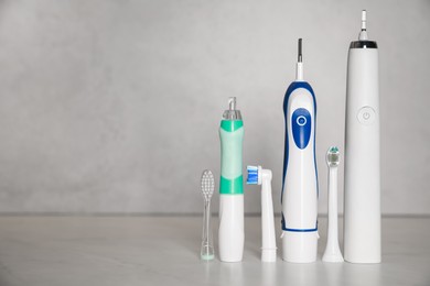 Photo of Electric toothbrushes and replacement brush heads on light background, space for text