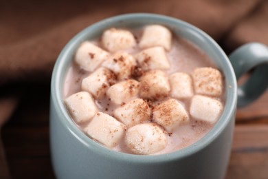 Cup of aromatic hot chocolate with marshmallows and cocoa powder on table, closeup