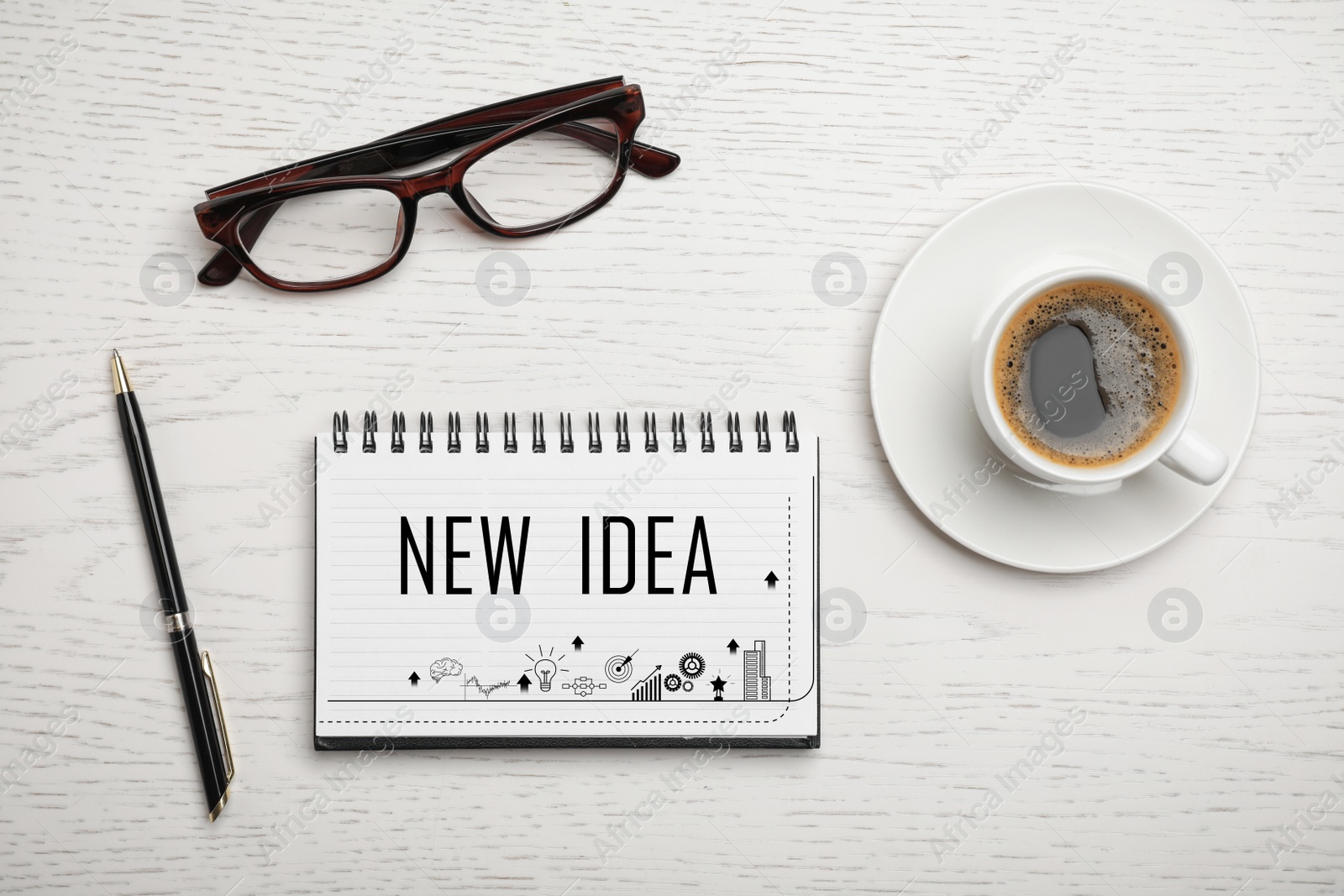 Image of Notebook with words NEW IDEA and cup of coffee on white wooden table, flat lay