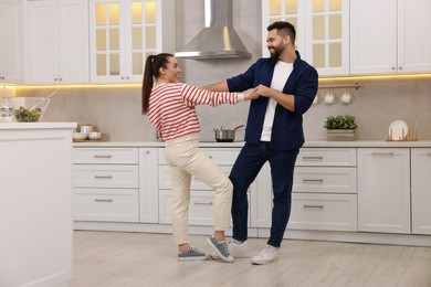 Photo of Happy lovely couple dancing together in kitchen