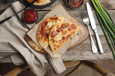 Delicious fried chebureki with ketchup served on wooden table, flat lay