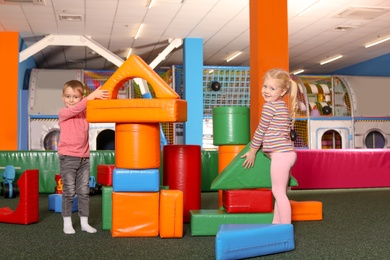 Cute children playing with colorful building blocks indoors