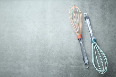 Two whisks on gray table, top view. Space for text