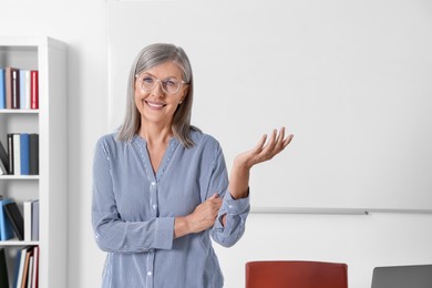 Photo of Portrait of happy professor near whiteboard in classroom, space for text