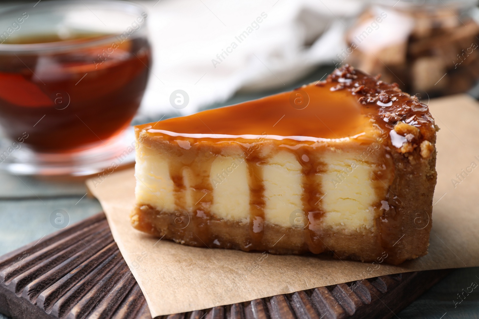 Photo of Piece of delicious cake with caramel on board, closeup