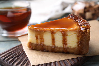 Photo of Piece of delicious cake with caramel on board, closeup