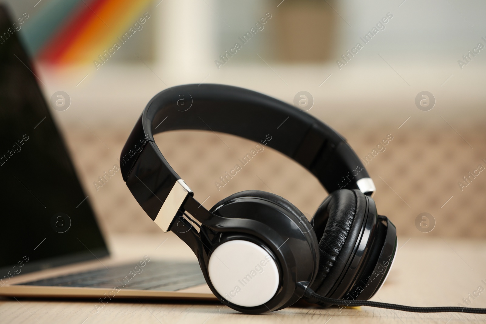 Photo of Modern headphones and laptop on table indoors