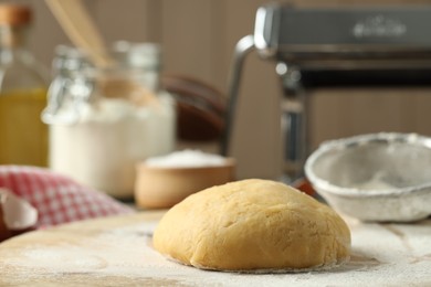 Photo of Raw dough for pasta and flour on table, closeup