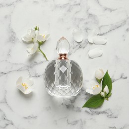Photo of Bottle of luxury perfume and fresh jasmine flowers on white marble table, flat lay