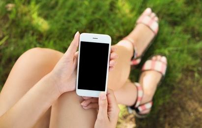 Photo of Woman using smartphone with blank screen outdoors, closeup. Mock up for design