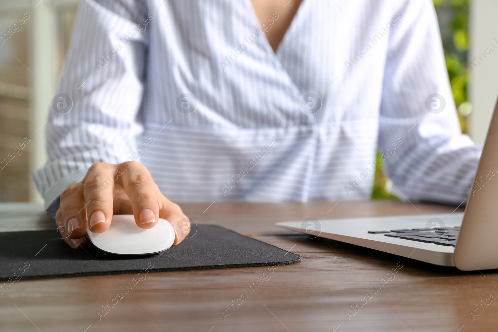 Photo of Woman using computer mouse with laptop at table, closeup