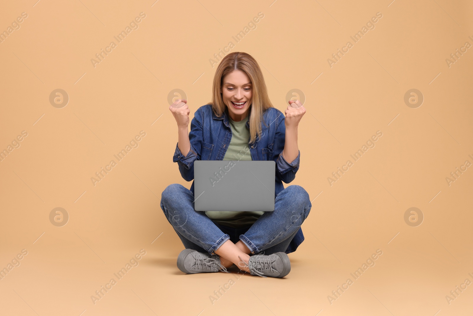 Photo of Emotional woman with laptop on beige background