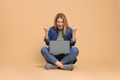 Emotional woman with laptop on beige background