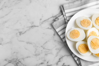 Photo of Tasty hard boiled eggs on white marble table, flat lay. Space for text