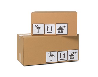 Photo of Two closed cardboard boxes with packaging symbols isolated on white. Delivery service