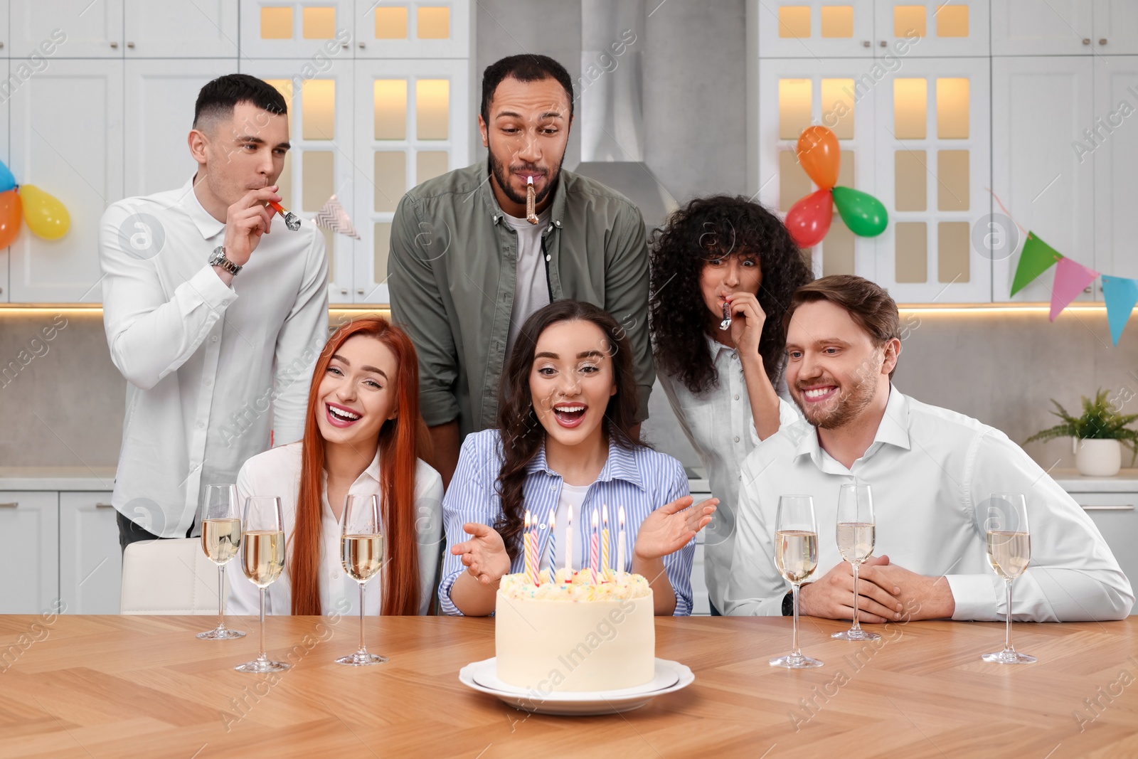 Photo of Happy friends with tasty cake celebrating birthday in kitchen
