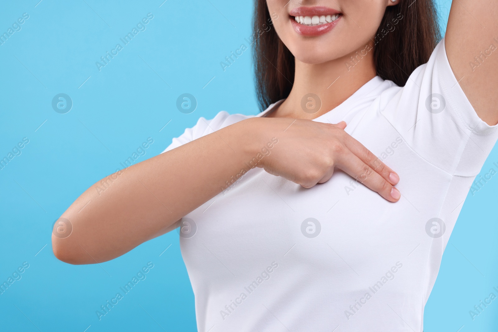 Photo of Woman doing breast self-examination on light blue background, closeup