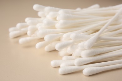 Many clean cotton buds on beige background, closeup