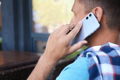 Man talking on smartphone in outdoor cafe, closeup