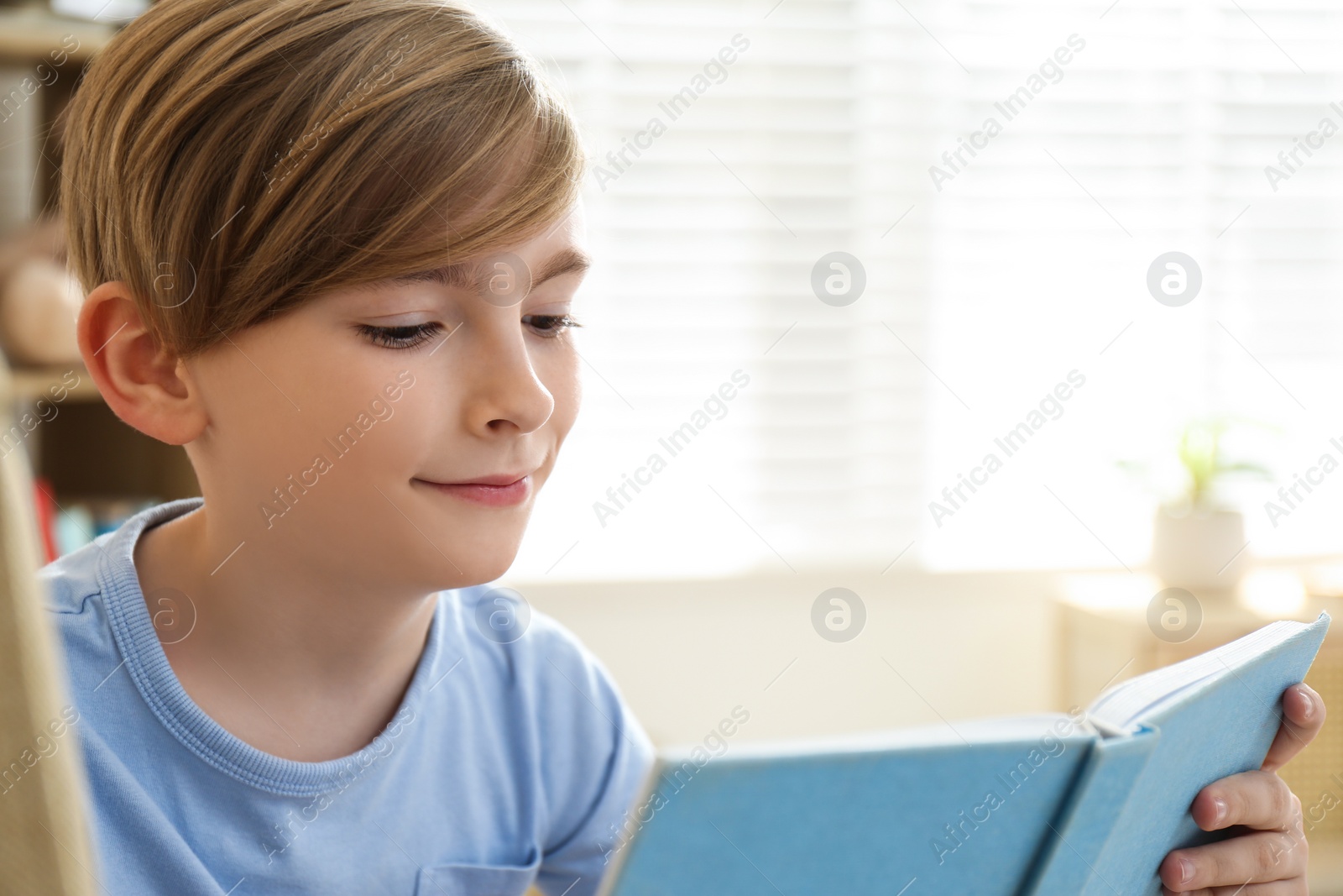 Photo of Cute little boy reading book at home