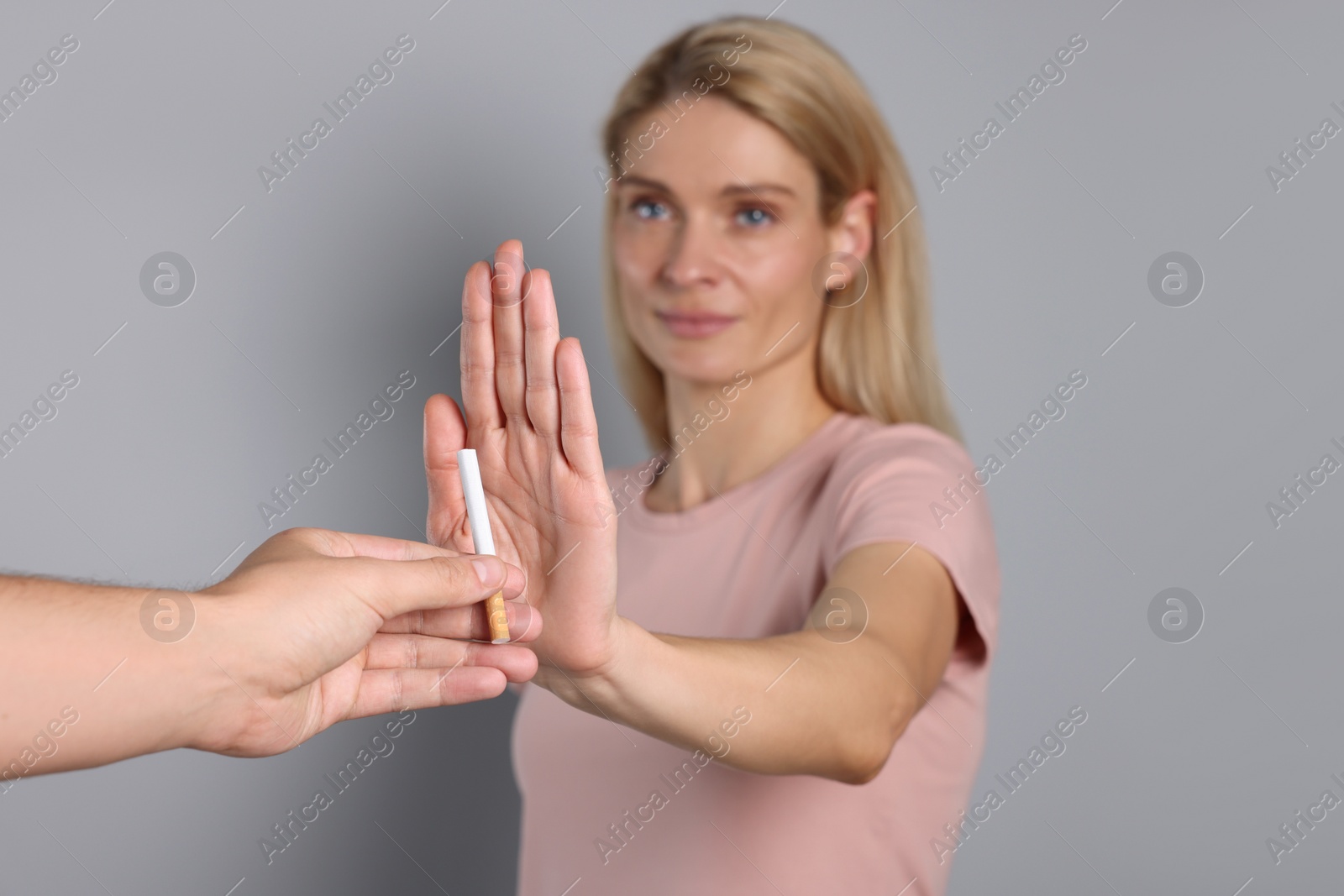 Photo of Woman refusing cigarette on light grey background, selective focus. Quitting smoking concept