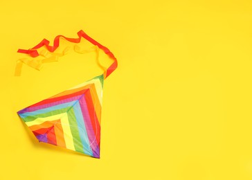Photo of Bright rainbow kite on yellow background, space for text