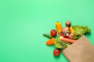 Photo of Different fresh vegetables on green background, flat lay. Space for text