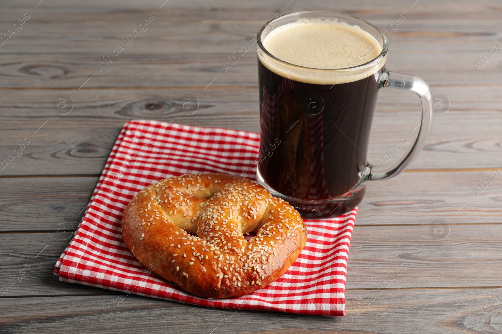 Photo of Tasty pretzel and glass of beer on wooden table