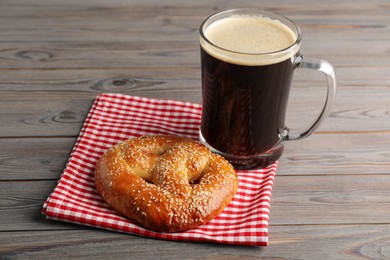 Tasty pretzel and glass of beer on wooden table