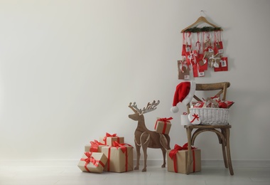 Advent calendar, Christmas gifts and decor near white wall indoors, space for text