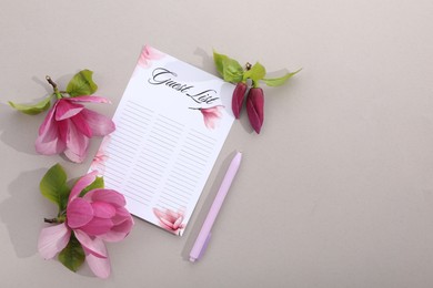 Photo of Guest list, pen and beautiful flowers on grey background, flat lay. Space for text