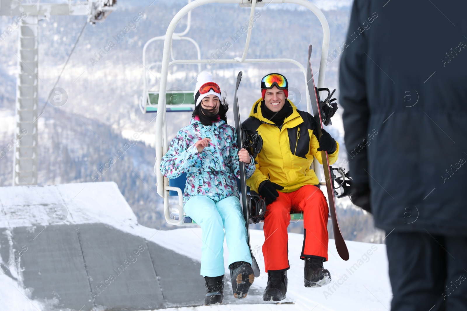 Photo of Couple using chairlift at mountain ski resort. Winter vacation