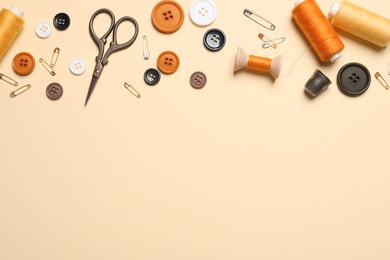Photo of Flat lay composition with scissors and other sewing accessories on light yellow background, space for text