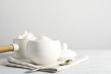 Photo of Dishware with sugar on white wooden table. Space for text
