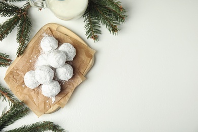 Christmas snowball cookies and fir branches on white table, flat lay. Space for text