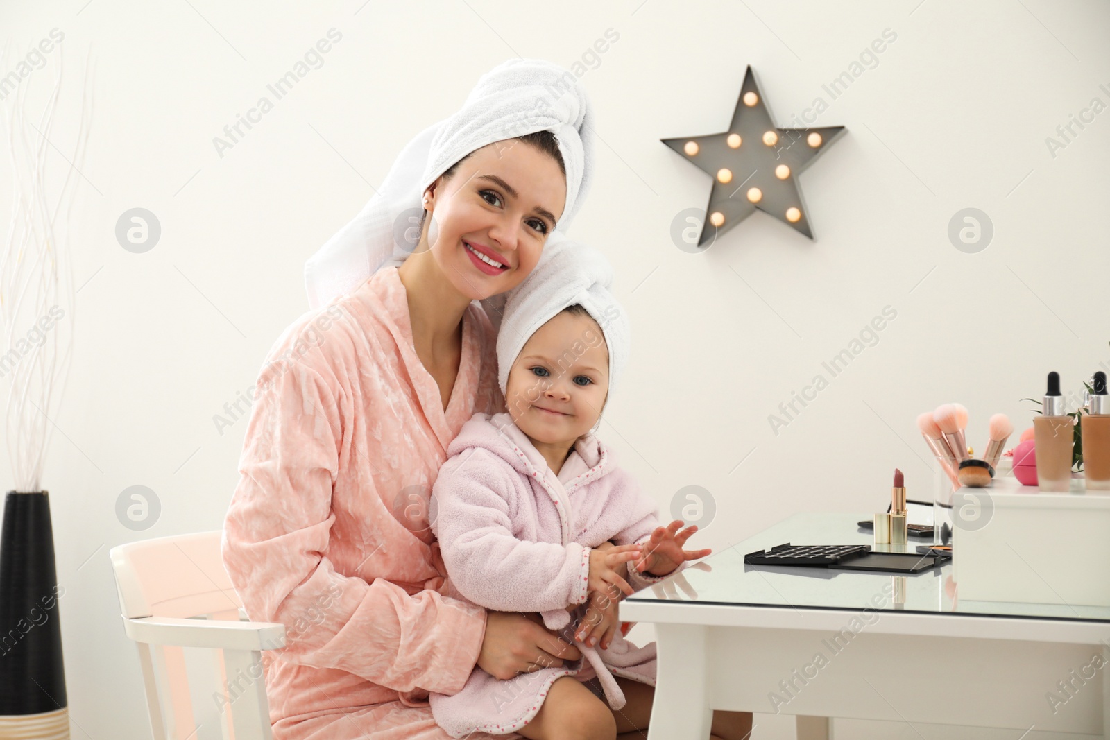 Photo of Young mother and little daughter at dressing table