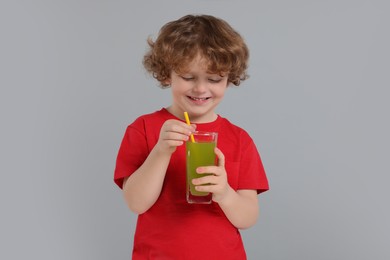 Photo of Cute little boy with glass of fresh juice on light gray background