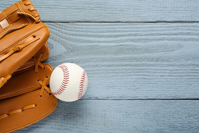 Photo of Leather baseball glove with ball on grey wooden table, top view. Space for text