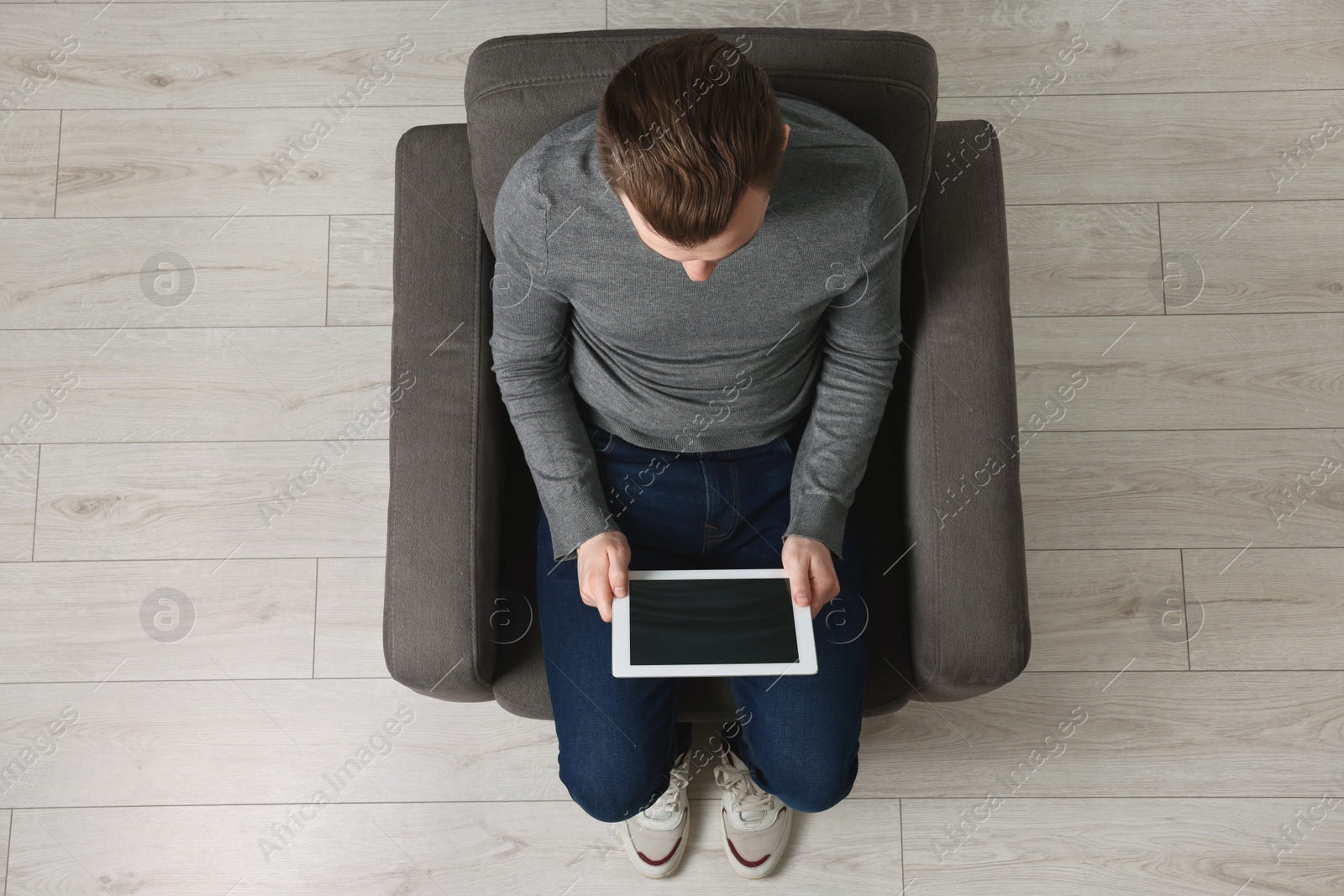 Photo of Man working with tablet in armchair, top view