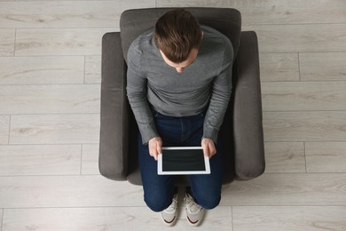 Man working with tablet in armchair, top view